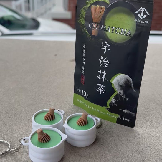 Short video demonstrating a 3D-printed matcha whisk bowl fidget toy keychain being pressed with a satisfying click, sitting beside Japanese matcha packaging.