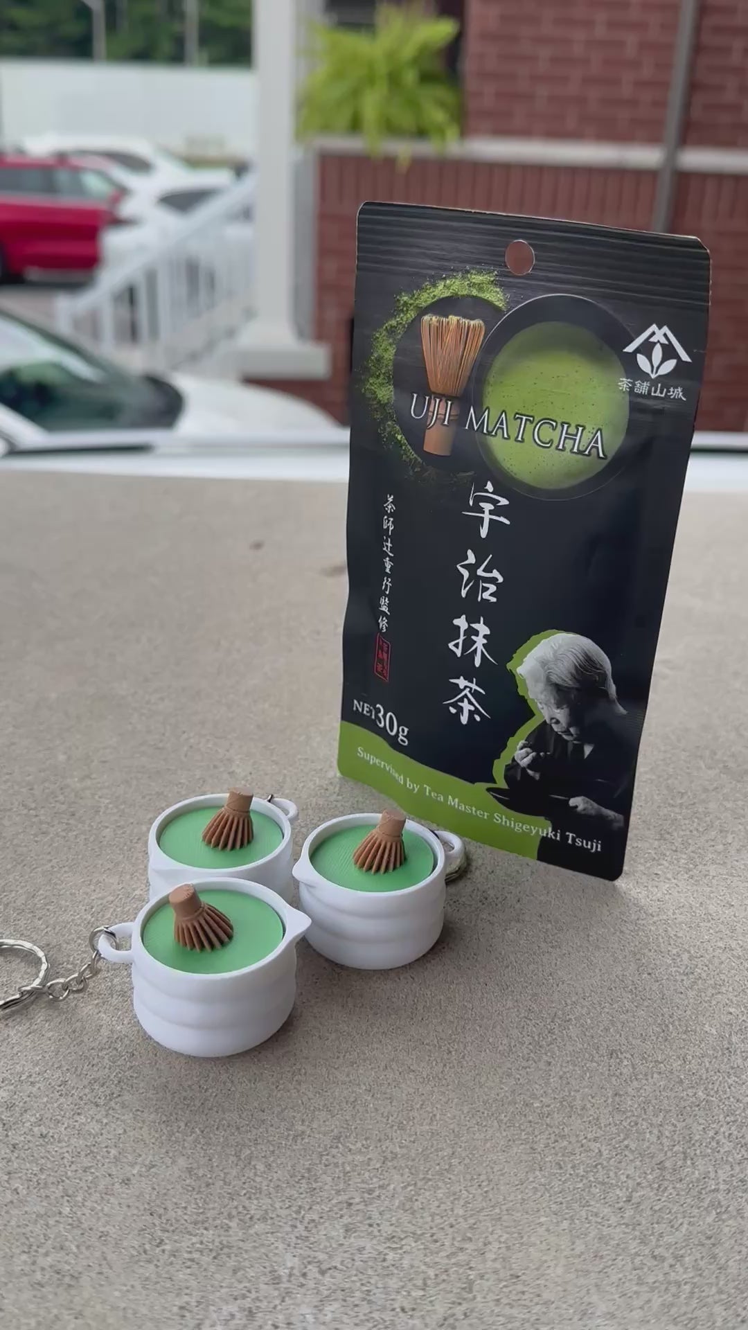 Short video demonstrating a 3D-printed matcha whisk bowl fidget toy keychain being pressed with a satisfying click, sitting beside Japanese matcha packaging.